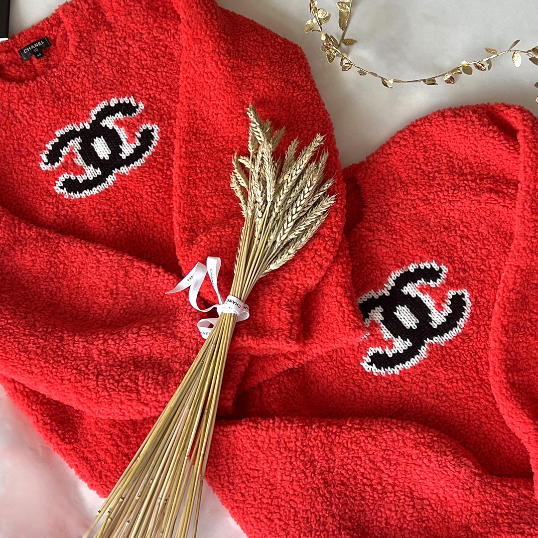 Red CHANEL knitwear composition with golden wheat and a decorative gold branch.